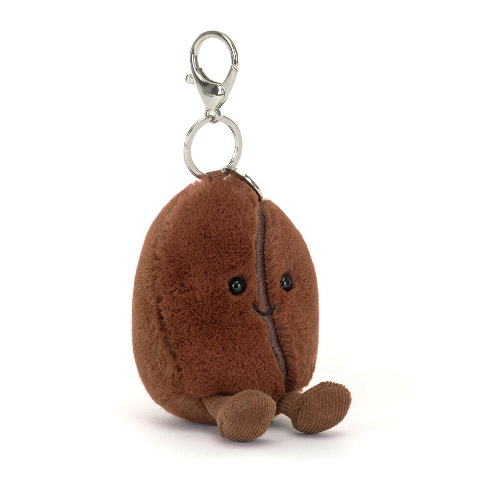A 45 degree view of a cute plush coffee bean keychain with smiling face, soft brown fabric, black eyes, and dangling feet, attached to a silver metal clip—perfect for bags, keys, or gifts.