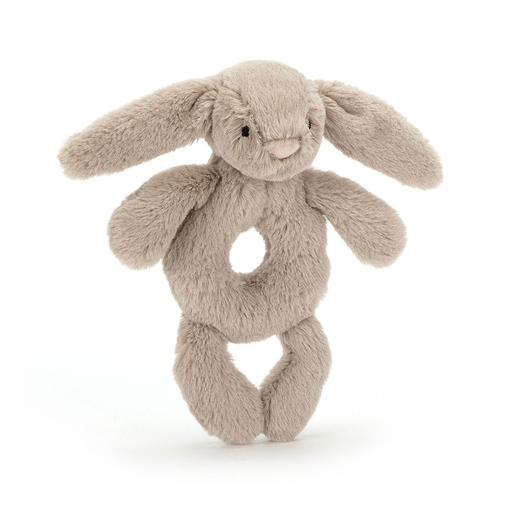 A front view of a soft beige plush bunny rattle toy with long floppy ears, a heart-shaped nose, stitched eyes, and a circular hole in the center for easy gripping, displayed on a white background.
