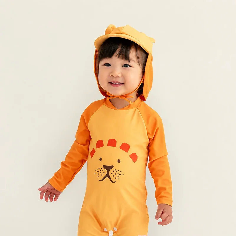Toddler wearing Le Petit Society Baby Lion Sunhat with lion ears and matching orange lion rash guard swimsuit with lion face graphic