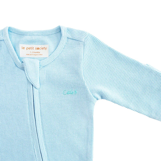 An organic baby zip sleepsuit in blue with a name embroidery personalisation, by Le Petit Society.