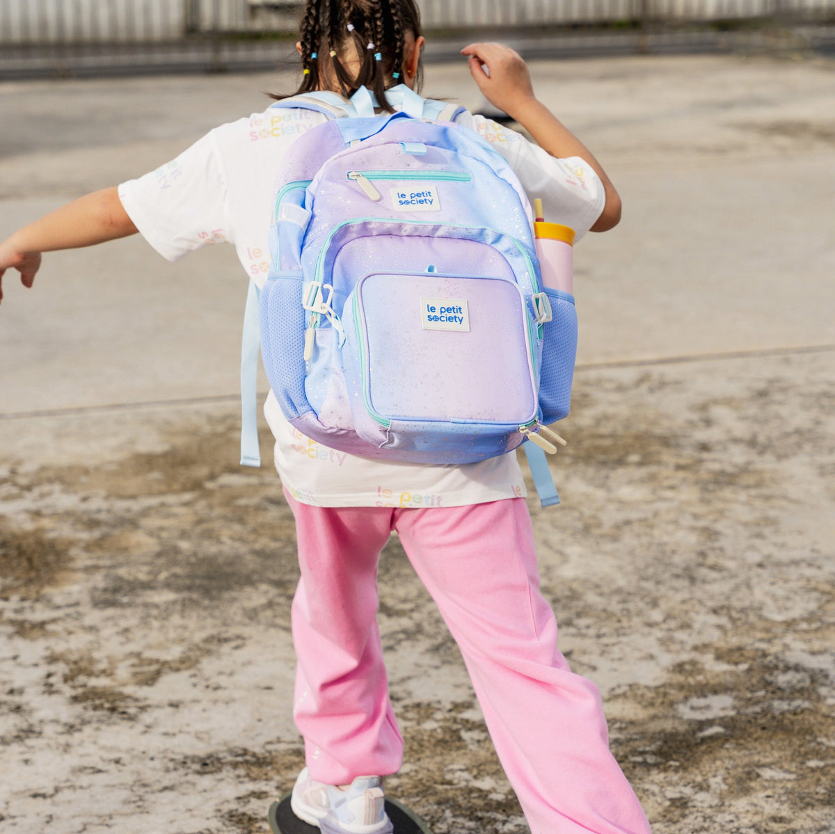 A primary school girl carrying the LPS kids single pocket school bag in an ombre galaxy design.
