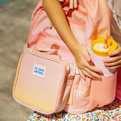 A kid storing her water bottle in the sleeve of her LPS kids double pocket backpack.