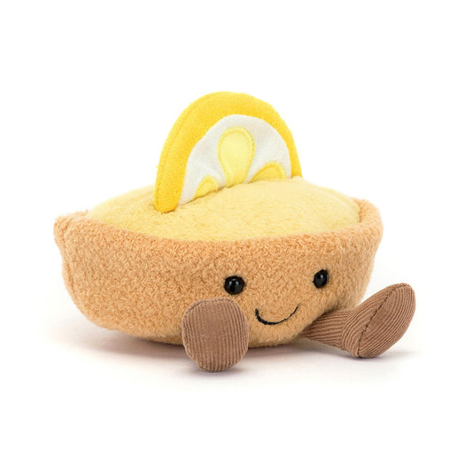 A 45 degree view of a cute plush toy shaped like a lemon pie with a smiling face, brown legs, and a soft yellow lemon slice on top. The stuffed dessert has a cozy, cheerful appearance perfect for gifting or decoration
