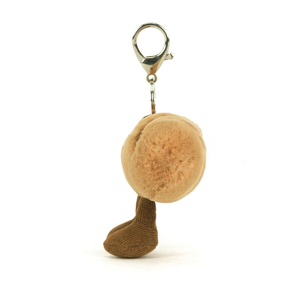 A side view of a plush baguette keychain with embroidered smile, soft brown legs, and corduroy accents, complete with a silver clip for easy attachment.