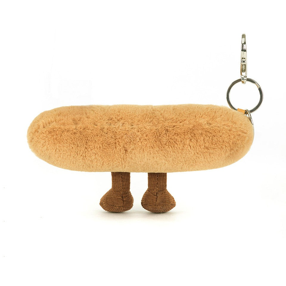 A back view of a plush baguette keychain with embroidered smile, soft brown legs, and corduroy accents, complete with a silver clip for easy attachment.