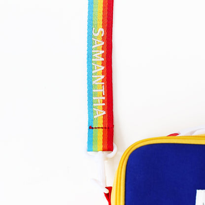 A close-up of a personalised name embroidery on a rainbow  bag strap from Le Petit Society.