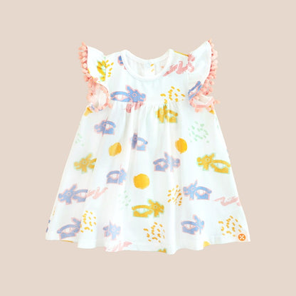 White girl’s flutter-sleeve dress from Le Petit Society with pink pompom trim and colorful dragon playground print and sun print in pastel blue, yellow, green, and pink.