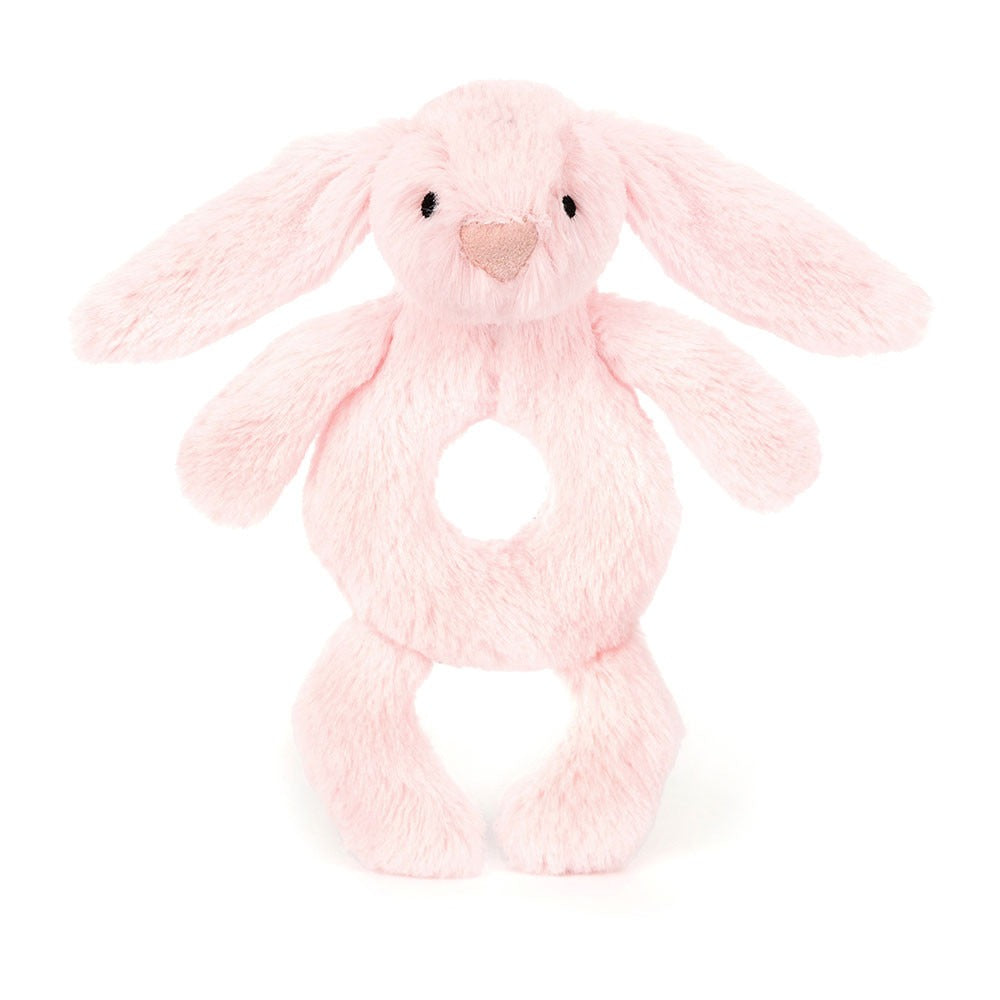 A front view of a soft pink plush bunny rattle toy with long floppy ears, a heart-shaped nose, stitched eyes, and a circular hole in the center for easy gripping, displayed on a white background.