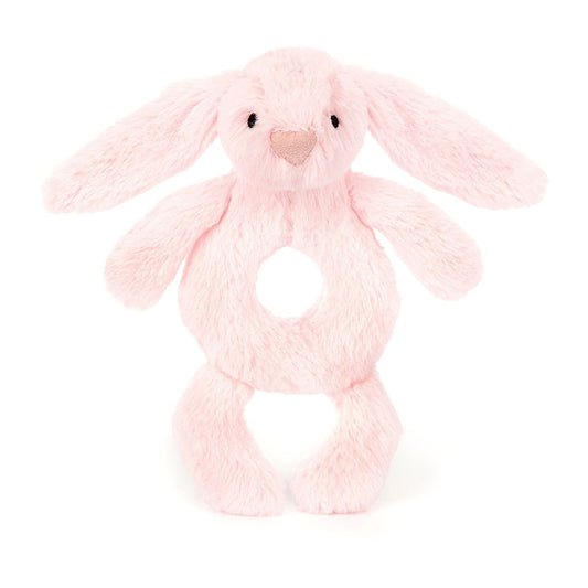 A front view of a soft pink plush bunny rattle toy with long floppy ears, a heart-shaped nose, stitched eyes, and a circular hole in the center for easy gripping, displayed on a white background.