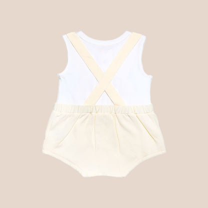 An animal-themed baby romper by Le Petit Society, featuring a sheep's face in beige at the front, complete with bottoms and cross back straps in beige over a white undershirt.