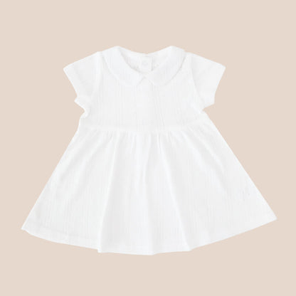 A baby girl dress from Le Petit Society. It comes with a peter pan collar and is made in a white pointelle cotton.
