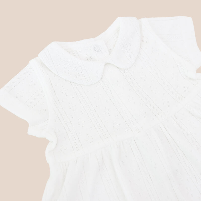 A baby girl dress from Le Petit Society. It comes with a peter pan collar and is made in a white pointelle cotton.
