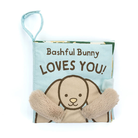 A soft fabric baby book with a bunny on the cover and fuzzy beige arms, titled "Bashful Bunny LOVES YOU!" 