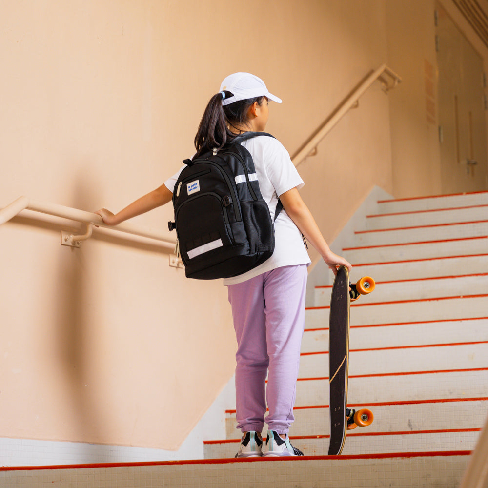 A primary school girl carrying the LPS kids double pocket school bag in cool black.