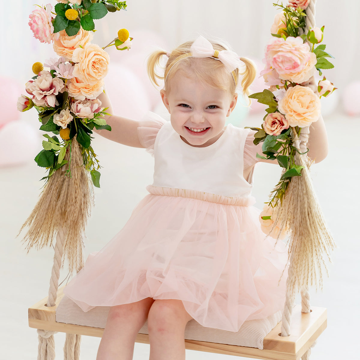 Flower girl bubble dress in soft pink tulle with flutter sleeves and gold elastic waistband