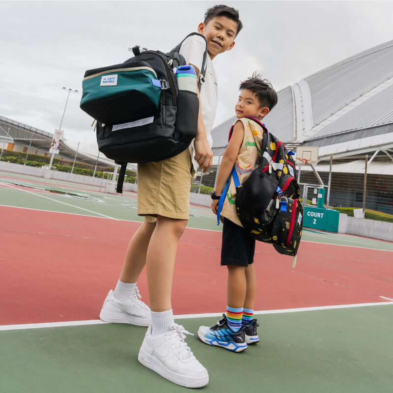 Two primary school boys carrying the essential school bundles from Le Petit Society.