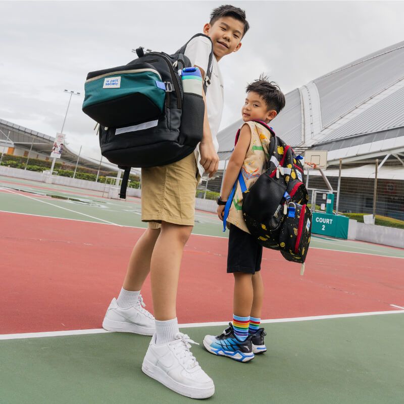 A primary school boy and a preschooler with school bag bundles from Le Petit Society.