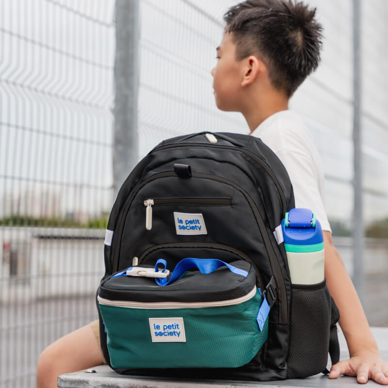 A primary school boy carrying the LPS double pocket school bag in cool black.