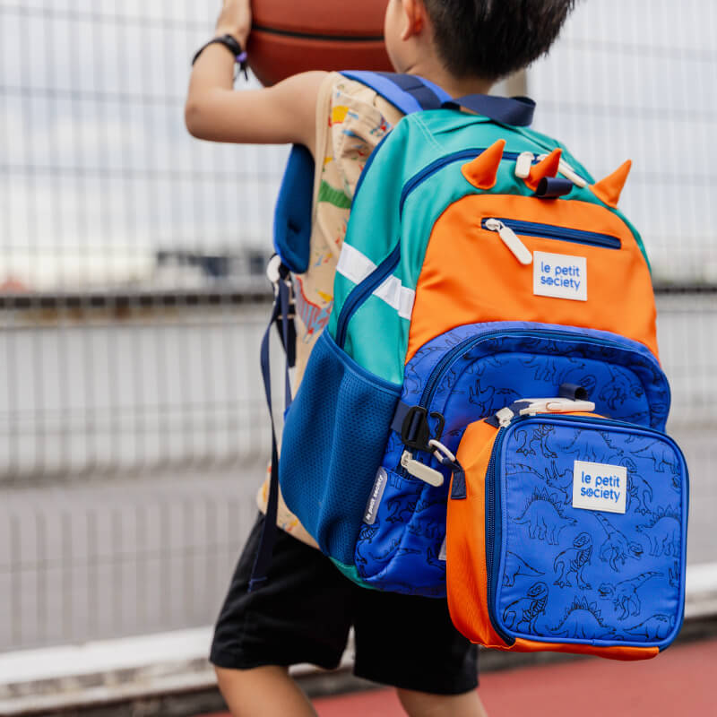 A sporty primary school playing basketball while carrying the LPS kids single pocket school bag.