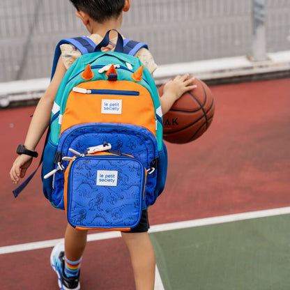 A primary schooler playing sports while carrying the single pocket school bag in a dinosaur design from Le Petit Society.