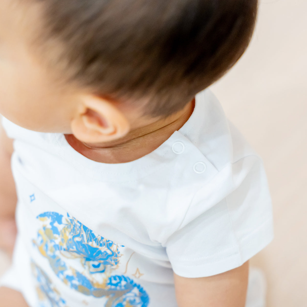 A close-up featuring the snap buttons of a baby romper in dragon print from Le Petit Society's Dragon Streetwear collection.