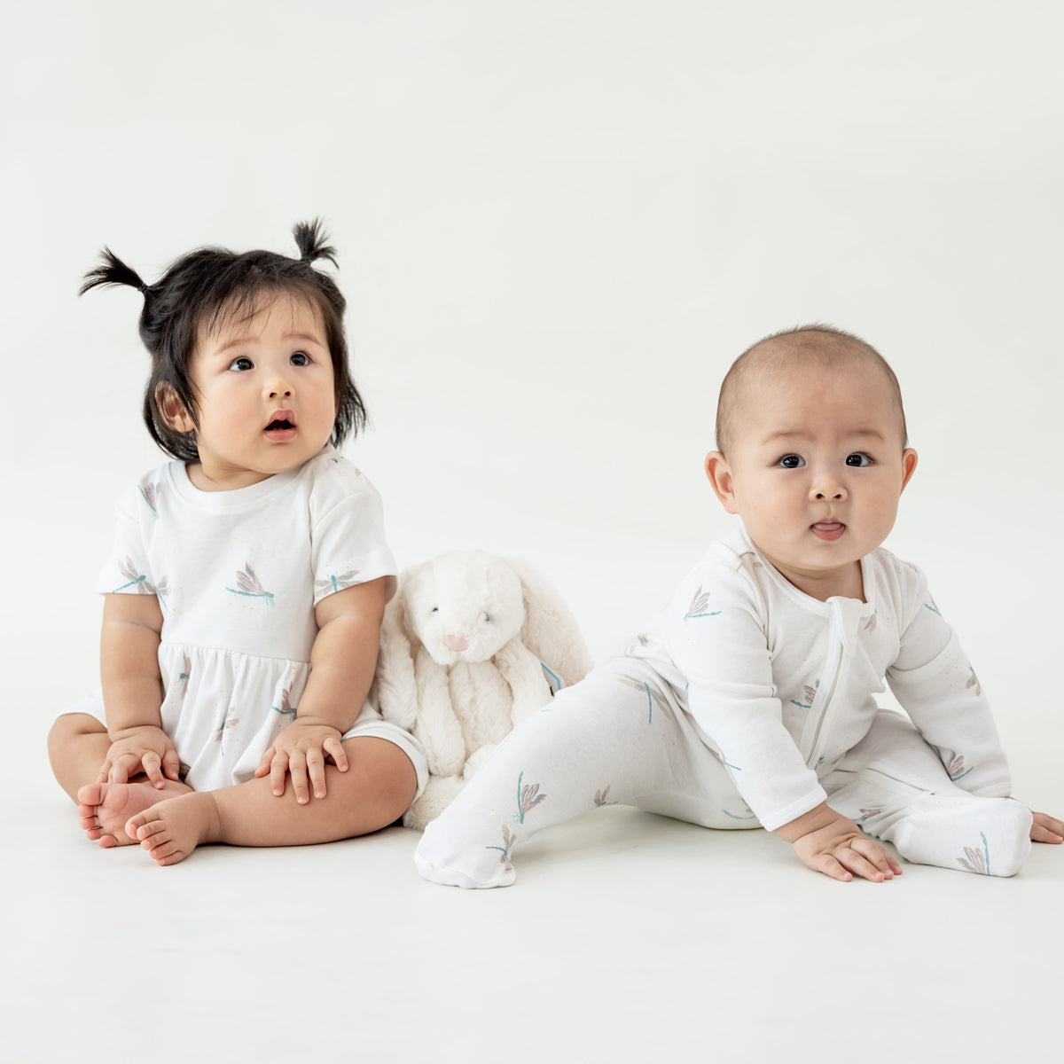 Two babies wearing pieces from Le Petit Society's organic baby line in dragonfly print. 