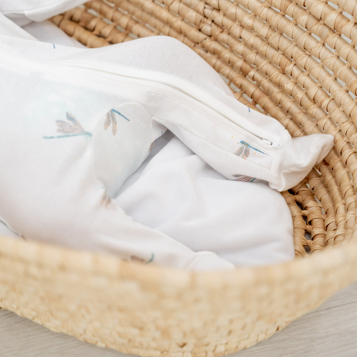 A close-up of the two-way zip that extends to the feet of Le Petit Society's organic zip sleepsuit in dragonfly print. 