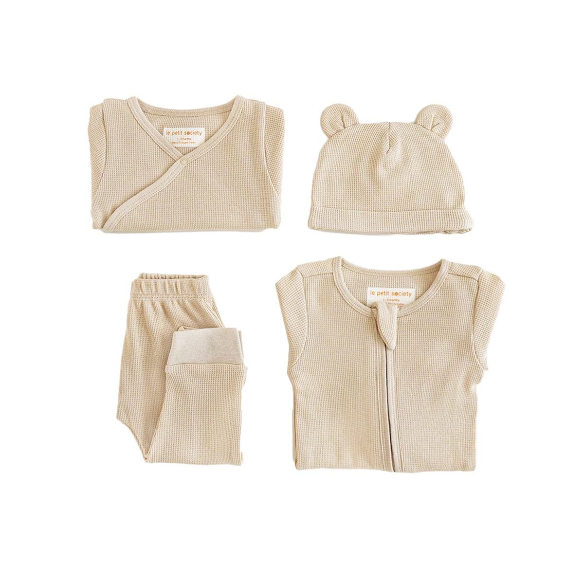 A baby organic essentials set in beige by Le Petit Society, consisting of a zip sleepsuit, kimono romper, leggings and bear hat.