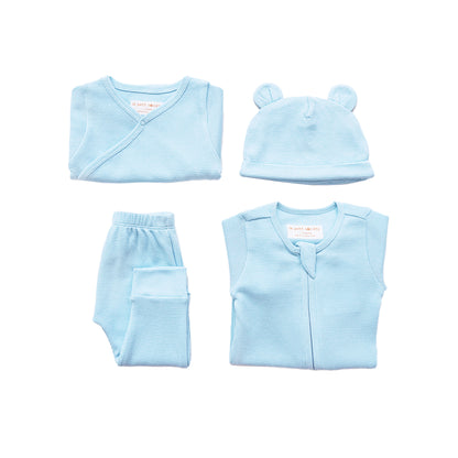 A baby organic essentials set in blue by Le Petit Society, consisting of a zip sleepsuit, kimono romper, leggings and bear hat.