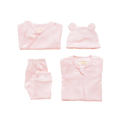 A baby organic essentials set in pink by Le Petit Society, consisting of a zip sleepsuit, kimono romper, leggings and bear hat.