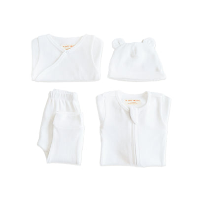 A baby organic essentials set in white by Le Petit Society, consisting of a zip sleepsuit, kimono romper, leggings and bear hat.