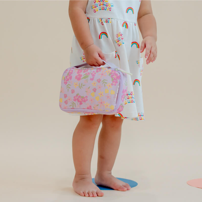 A toddler carrying a purple explorer pencil case and pouch with a floral print.