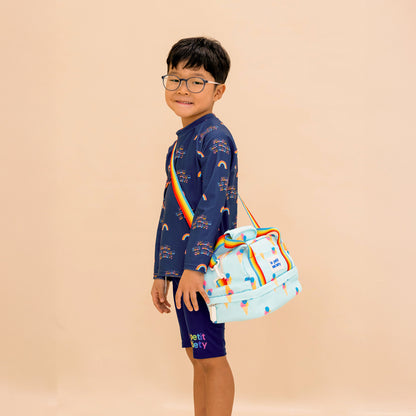 A primary school boy carrying a blue thermal lunch bag with an ice-cream print and rainbow straps.