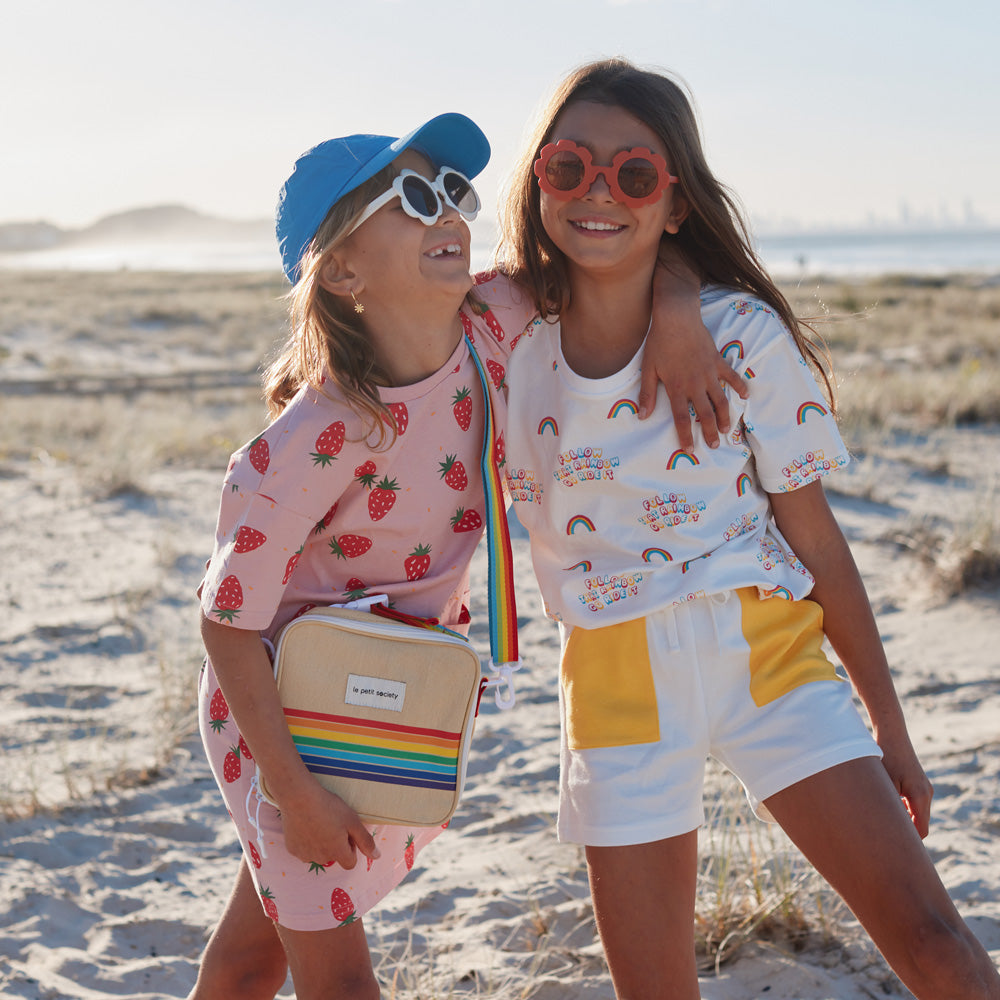 Two primary school girls with clothes and a rainbow thermal lunch bag from Le Petit Society.