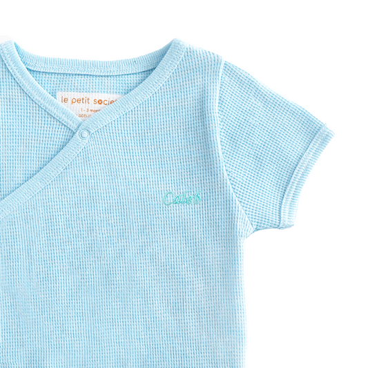 A baby organic kimono romper in blue by Le Petit Society.
