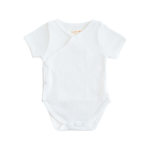 A baby organic kimono romper in white by Le Petit Society.