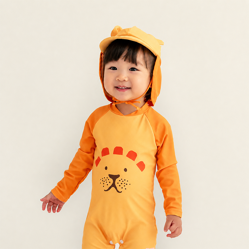 Toddler wearing Le Petit Society Baby Lion Sunhat with lion ears and matching orange lion rash guard swimsuit with lion face graphic