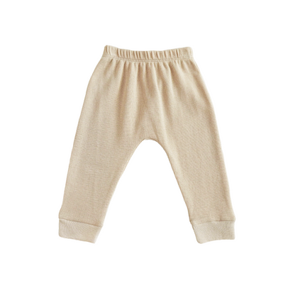 A pair of organic baby leggings in beige by Le Petit Society.