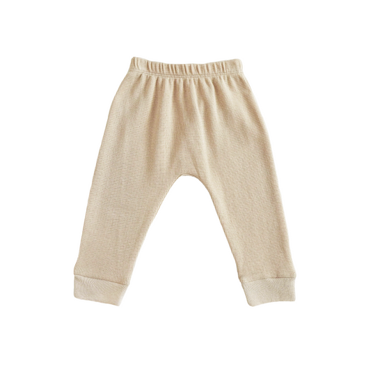 A pair of organic baby leggings in beige by Le Petit Society.