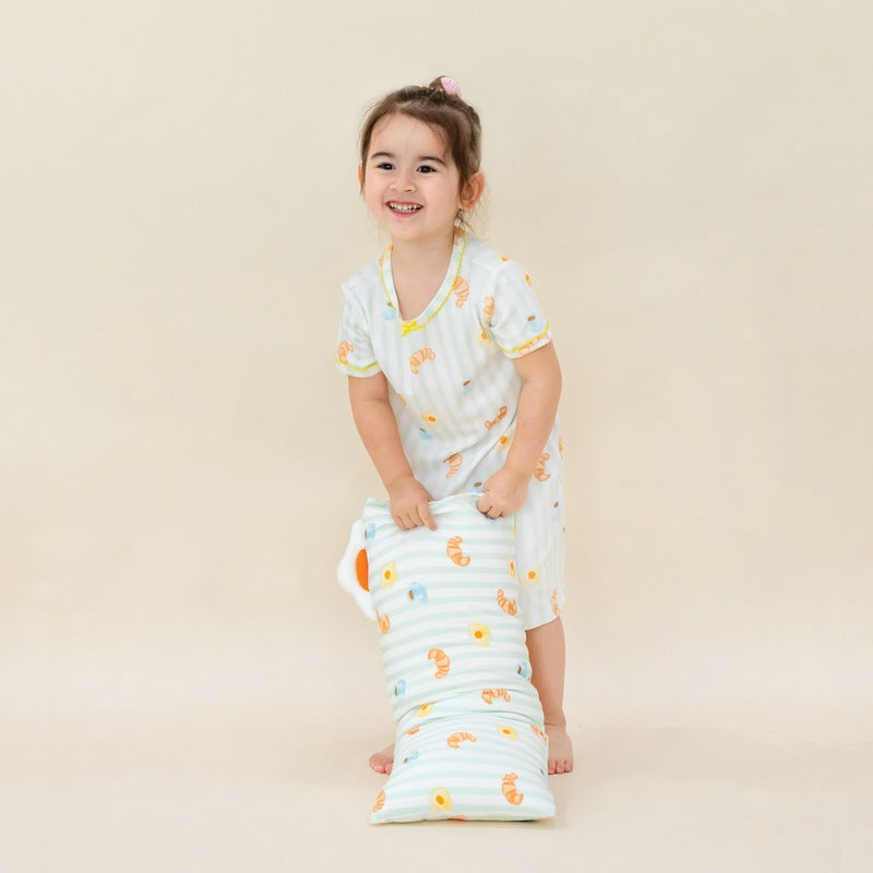 A little girl wearing a bamboo fabric dress featuring pastel green stripes and a print of breakfast food by Le Petit Society.