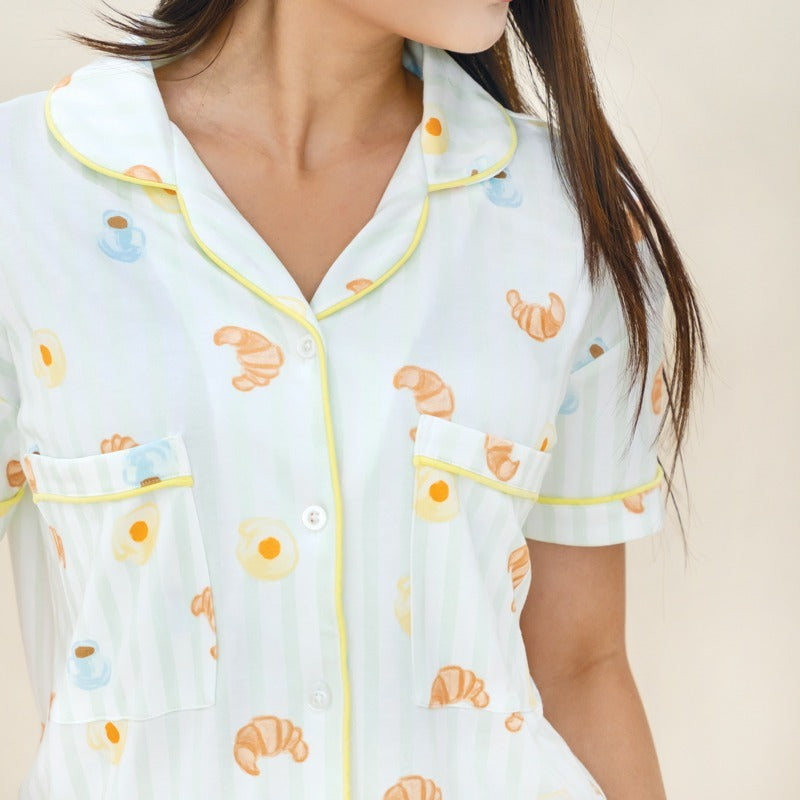 A close-up of a ladies bamboo pyjamas set from Le Petit Society, featuring a print of breakfast food, pastel green stripes and yellow trims.