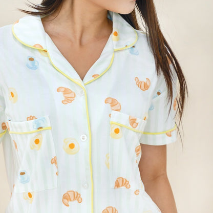 A close-up of a ladies bamboo pyjamas set from Le Petit Society, featuring a print of breakfast food, pastel green stripes and yellow trims.