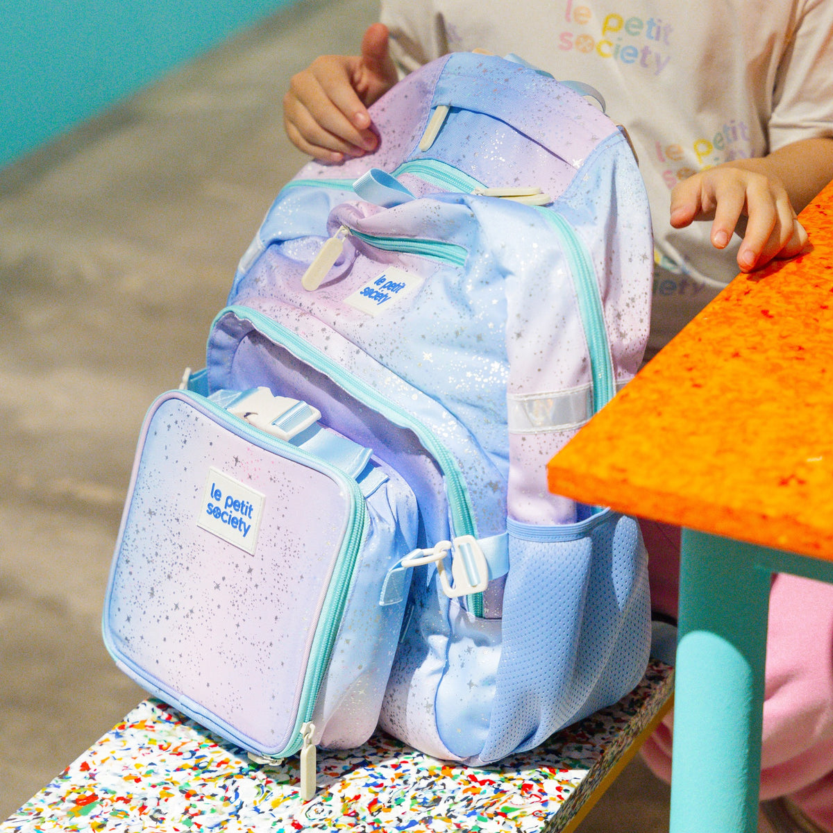 A child holding to the LPS kids single pocket school bag in an ombre galaxy design.