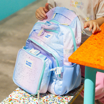 A child holding to the LPS kids single pocket school bag in an ombre galaxy design.
