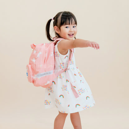A toddler girl carrying a pink unicorn print preschool bag.