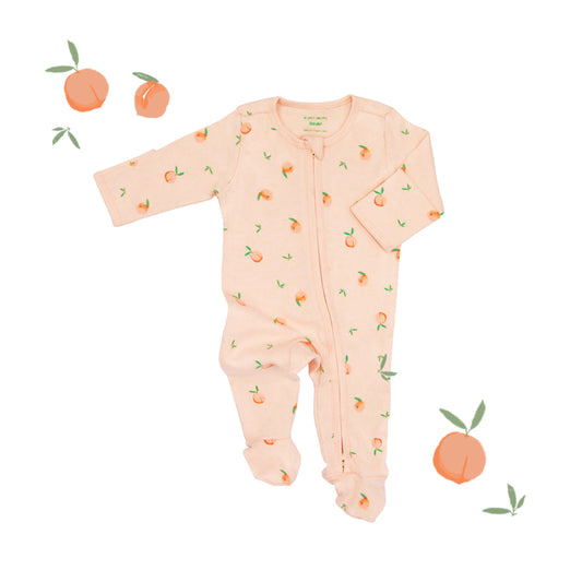 An organic baby zip sleepsuit from Le Petit Society. It is coral pink in colour, with a print of peaches and foldable mittens and footies.