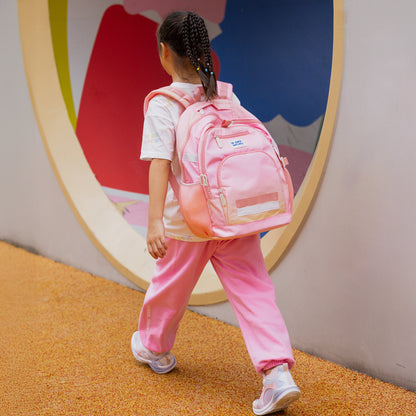 A primary school girl carrying the LPS kids double pocket school bag in pink and yellow.