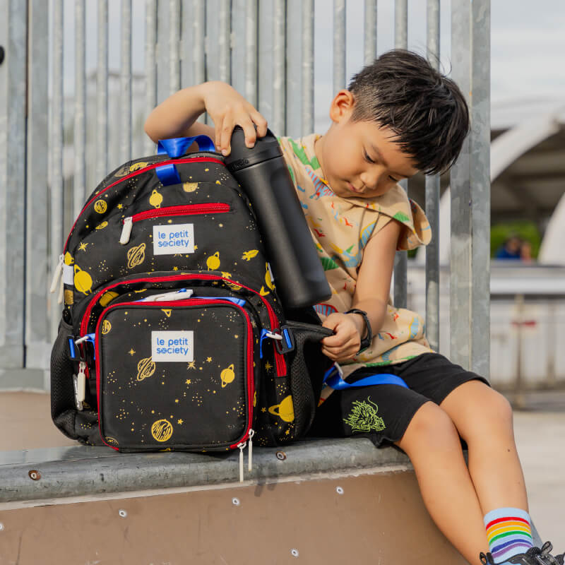 A primary school boy with the LPS kids single pocket school bag in planet print.