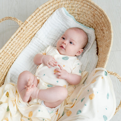 A baby wearing a kimono romper by Le Petit Society, featuring a print of planets over a cream base. 