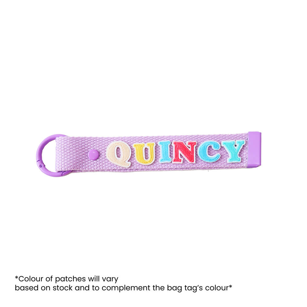 Le Petit Society's customisable purple bag tag with name patches.